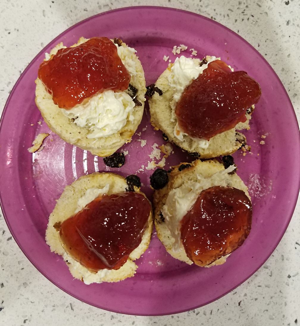Scones with strawberry jam and home-made clotted cream, ready to eat. These scones are served 
